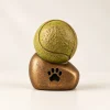 Bronskleurige dierenurn met pootafdruk en een tennisbal erbovenop.