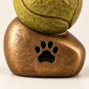 Zampetta™ dierenurn: bronskleurige voet met pootafdruk en tennisbal van dichtbij